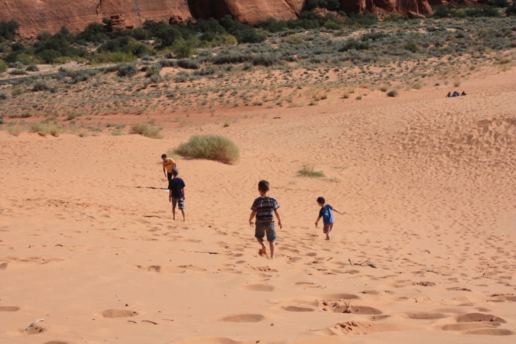 Boys running on the snow canyon sand dunes