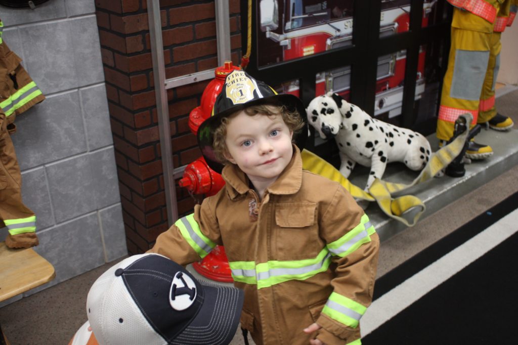 A boy putting on a fire fighter suit