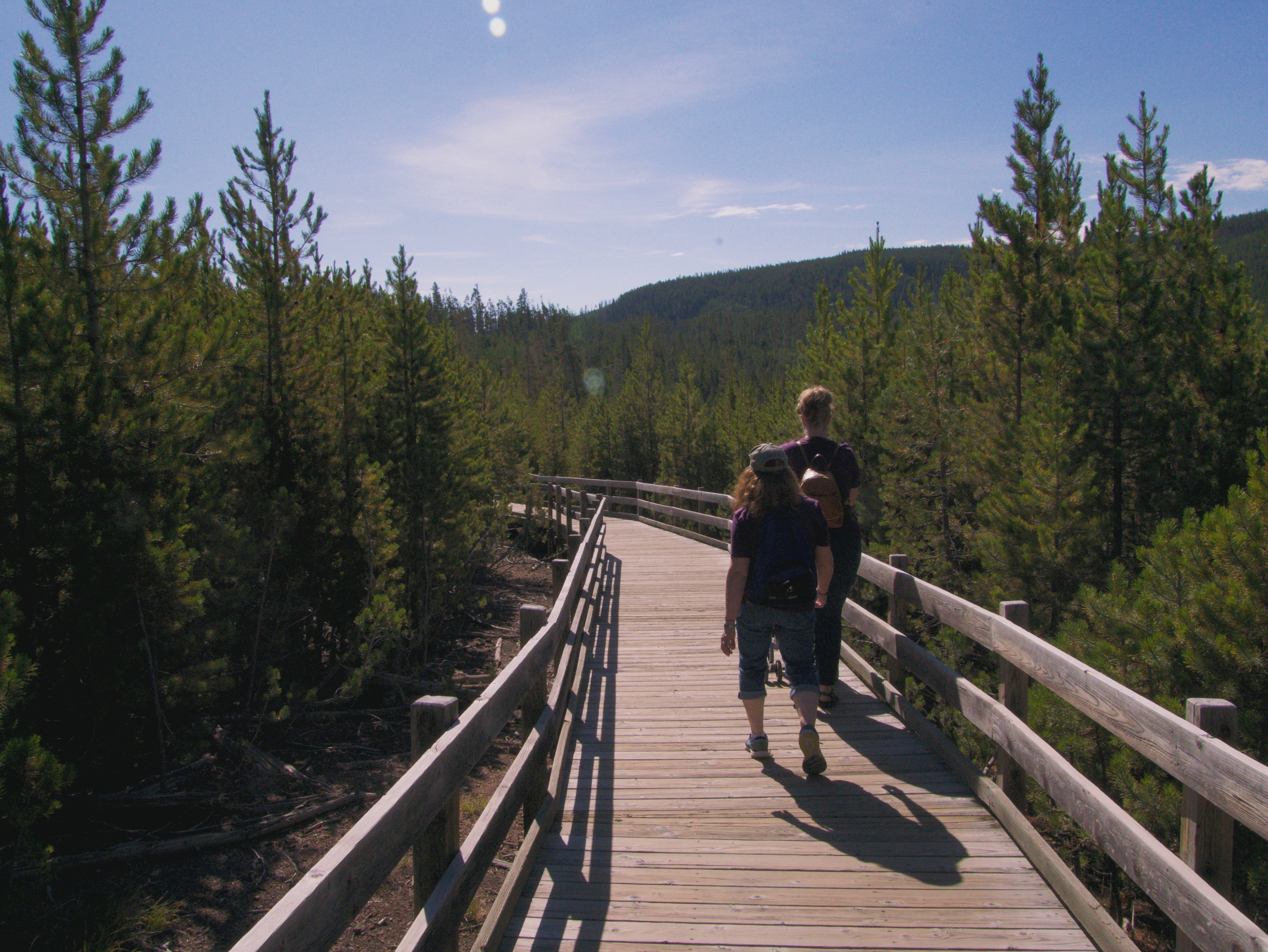 Two people walking on the boardwalk at the Norris Geyser Basin